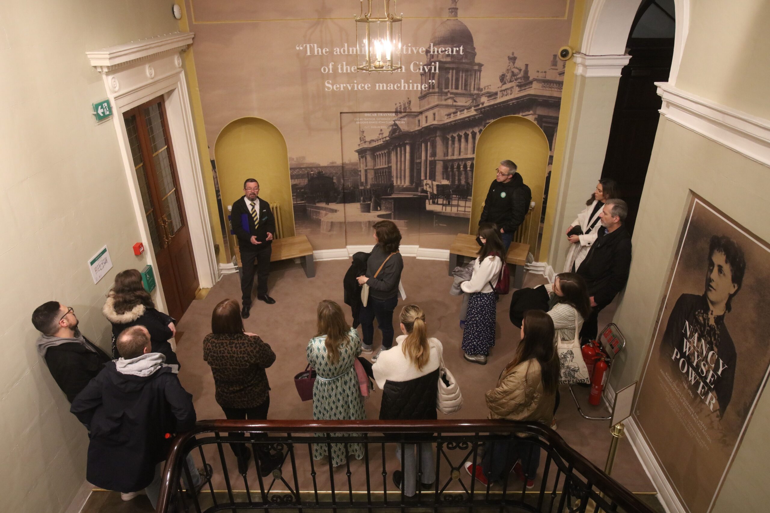 people listening to tour of exhibition from guide inside a room of the Custom House