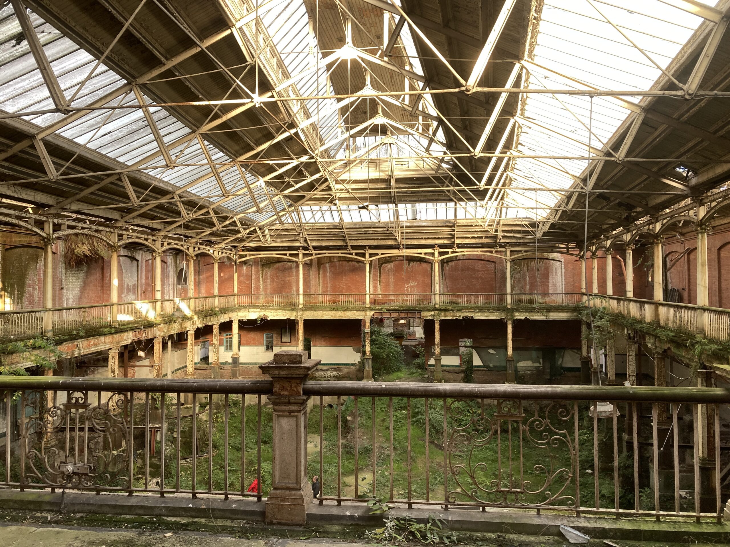 Interior of derelict market with green foliage taking over the groung