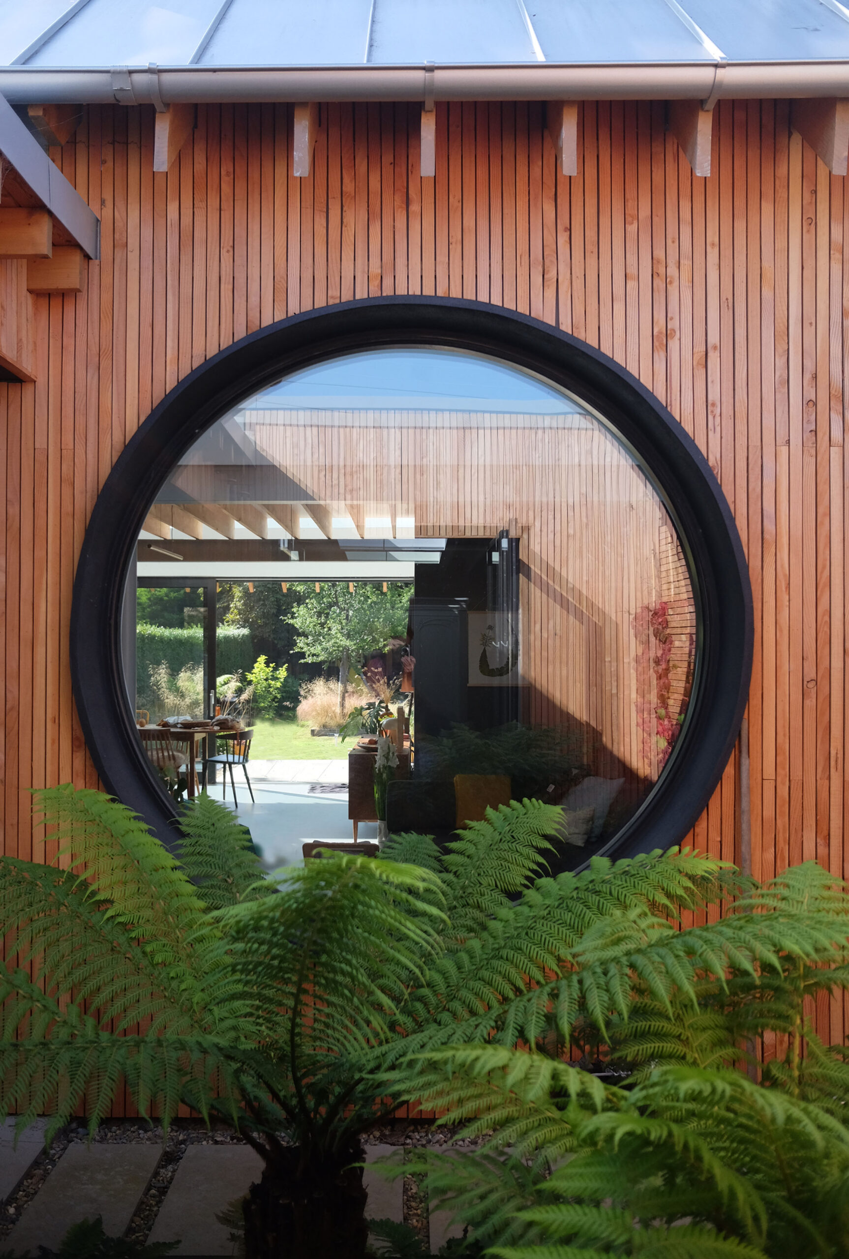 Courtyard round window outlooking house and with fern plant on the foreground