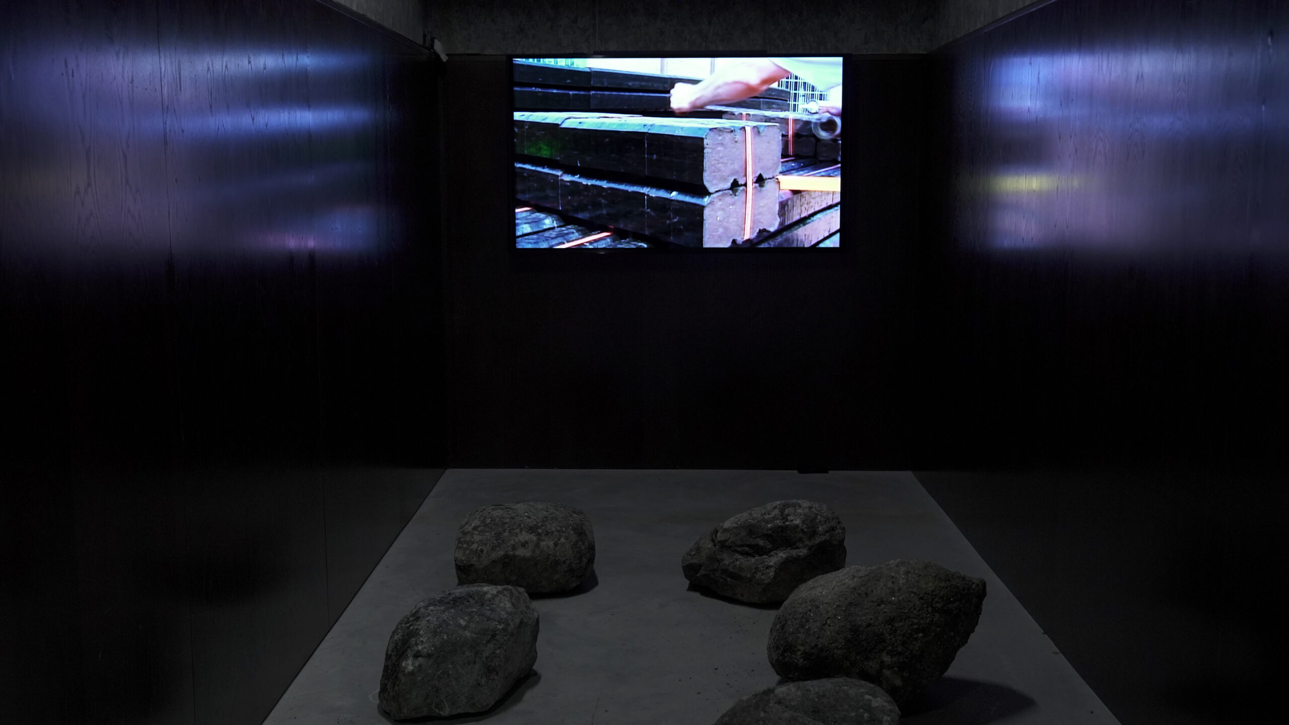 Dark room with film projection. Large rocks on the floor
