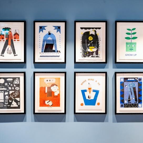 8 colorful framed prints hanging on a blue wall
