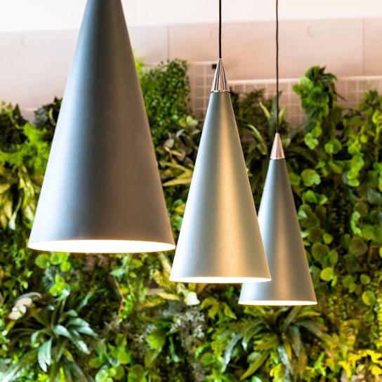 Three metal lamps hanging with green foliage in the background