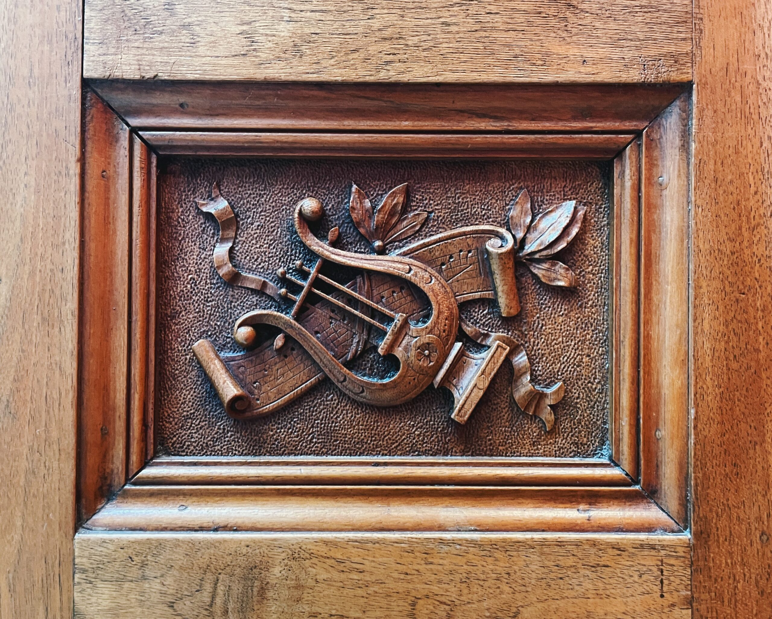 Carved wooden panel with an instrument and sheet music