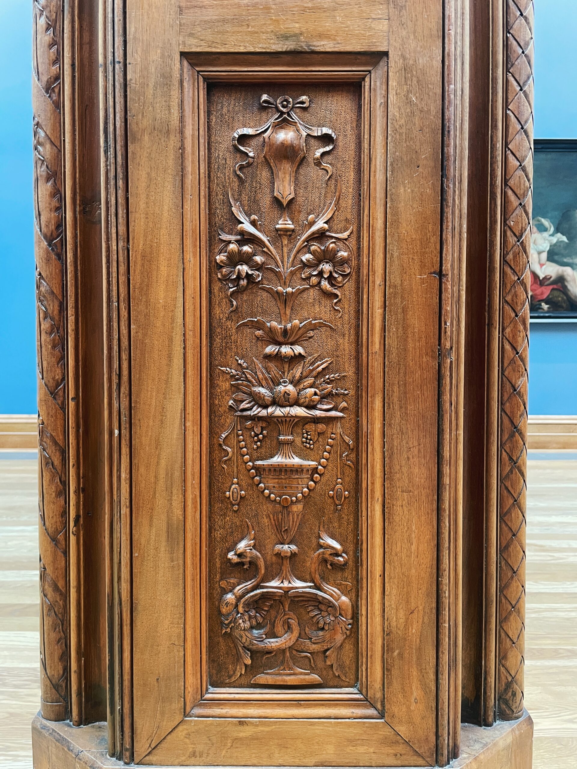 Carved doorframe with a bird on top and various flowers and vases underneath