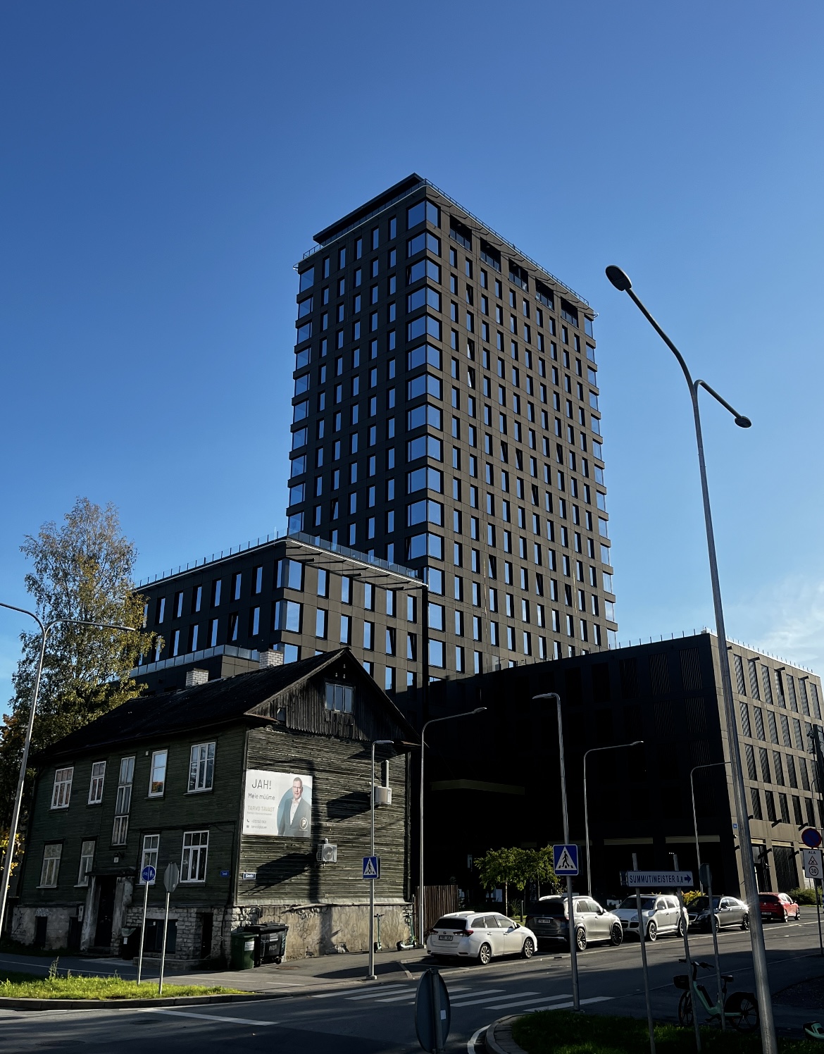 A traditional wooden house surrounded by a modern high-rise office and accommodation buildings